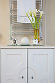 Scented candles and calla lilies on white bathroom cabinet London UK