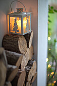 Log pile with candle lantern in porch of Hampshire cottage UK