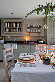 Tellerablage über der Spüle mit upgecycelten Stühlen an einem für das Weihnachtsessen gedeckten Tisch in einem Haus in Surrey UK