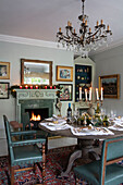 Oak wood dining table below chandelier with walls in Spearmint by Little Greene Grade II listed Georgian country house West Sussex UK