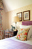 Floral cushion on bed with framed butterfly prints Wales UK