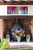 Woodburner in exposed brick fireplace with artwork and flowers Surrey UK