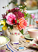 Schnittblumen auf gehäkelter Tischdecke mit Teetasse in einem Haus auf der Isle of Wight, UK