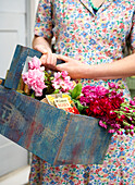Woman carries cut flowers in blue crate Isle of Wight, UK
