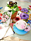 Teetasse aus Porzellan und Primel mit Grußkarte auf Tischset aus Nadelspitze Isle of Wight, UK
