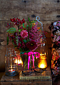 Lit candle and cut flowers with hurricane lamp on books in Autumn UK