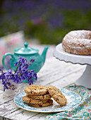 Biscuits and cake with bluebells and teapot (Hyacinthoides non-scripta)