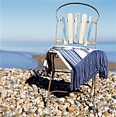 Stuhl im Vintage-Stil mit Decke an einem Einzelstrand