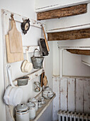 Aufbewahrung im Untergeschoss mit alten Brettern, an denen Töpfe, Pfannen und Bürsten hängen