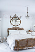 Schlafzimmer im skandinavischen Stil mit abgenutzter Lackierung, Bett und Kommode im Vintage Stil und großem vergoldeten Spiegel im Louis-IV-Stil