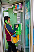 Woman using public payphone
