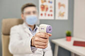 Doctor using infrared thermometer