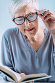 Senior woman reading a book whilst wearing reading glasses