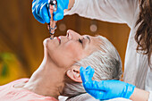 Senior woman receiving jaw treatment with meridian pen