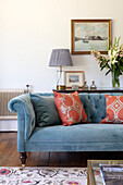 Blue upholstered sofa with blue and orange throw pillows