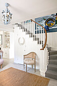 Staircase with striped runner, large picture and chandelier