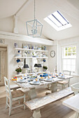 Country-style dining room with set table, shelves and skylight