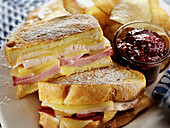 Monte Cristo sandwich with tureky ham, cheese, raspberry jam and potato chips on the side
