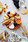 Cheese board with crackers, grissini, salami and grapes
