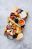 Cheese board with crackers, salami, grissini, grapes and dried apricots
