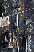 Vintage gardening tools on wooden wall with lantern and candle