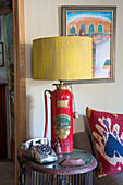 Upcycled table lamp made from old fire extinguisher next to rotary dial telephone on side table