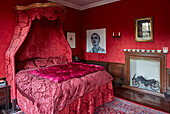 Dramatisches Himmelbett aus rotem Damast im Schlafzimmer mit roter Tapete