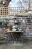 Gartendekoration auf Tisch und an vintage Ziegelmauer