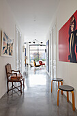 White hallway with polished concrete floor, seating furniture, and modern art