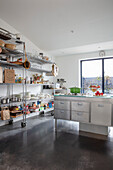 Floor-to-ceiling open shelving and center kitchen island in a light kitchen