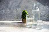 Mineralwasser in Karaffe und Gläsern auf grauem Betontisch