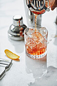 Old Fashioned Cocktail in ein Glas giessen