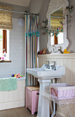 Pedestal washbasin below mirror and bathtub with shower curtain