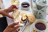 Scone with clotted cream and strawberry jam served with a cup of tea