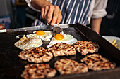 Burger patties and fried eggs on the grill