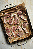 Lamb chops uncooked with thyme and salt in a tray