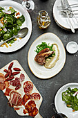 Lamb cutlet with a green bean salad, charcuterie and a leaf salad. A group of dishes