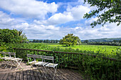 Terrace with white folding chairs and view of green landscape