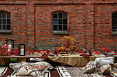 Herbstlich gedeckter Picknicktisch und Kelimteppich mit Kissen vor Backsteinhaus im Garten