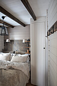 Country-style bedroom with wood paneling and exposed beams