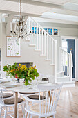Bright dining area with white staircase and crystal chandelier