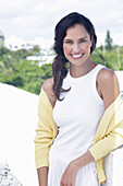 Dark-haired woman in white top and yellow cardigan