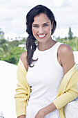 Dark-haired woman in white top and yellow cardigan