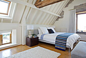 Wooden floor and exposed beams in the bright attic bedroom