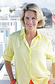 Blonde Frau in gelbem Hemd auf der Terrasse