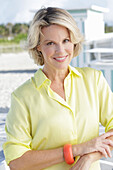 Blonde Frau in gelbem Hemd auf der Terrasse