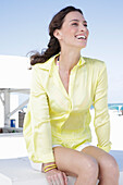 Brunette woman in yellow blouse and white shorts on the beach