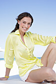 Brunette woman in yellow blouse and white shorts on the beach