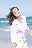 Brunette woman in pink striped blouse and light shorts on the beach