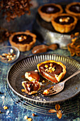 A part eaten chocolate caramel tart on a plate topped with chocolate balls and golden stars